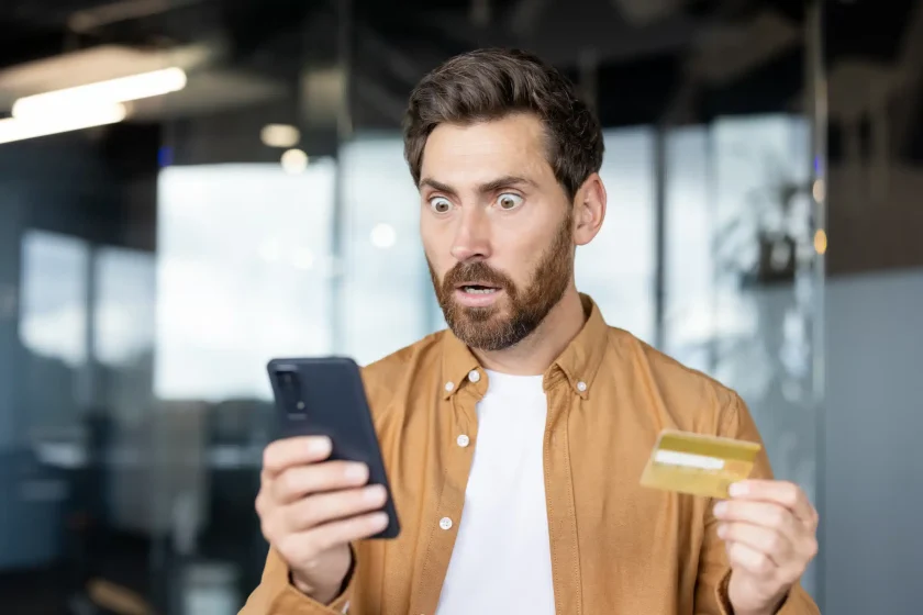shocked-man-looking-at-phone-holding-credit-card